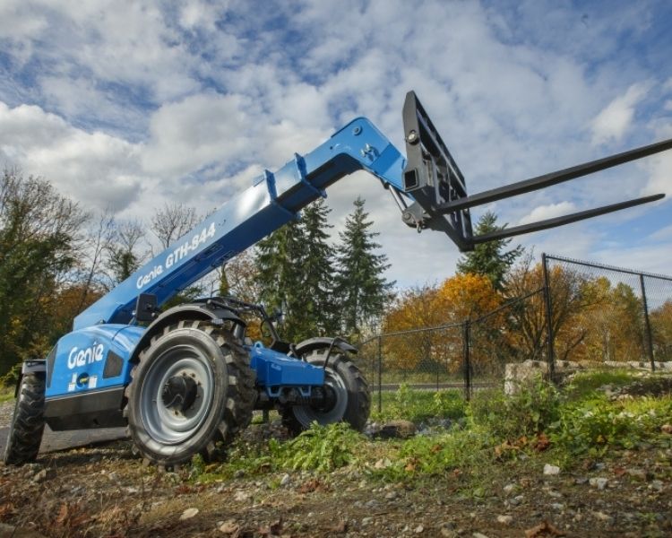 A genie telehandler outdoors in a field with nothing on the forks.