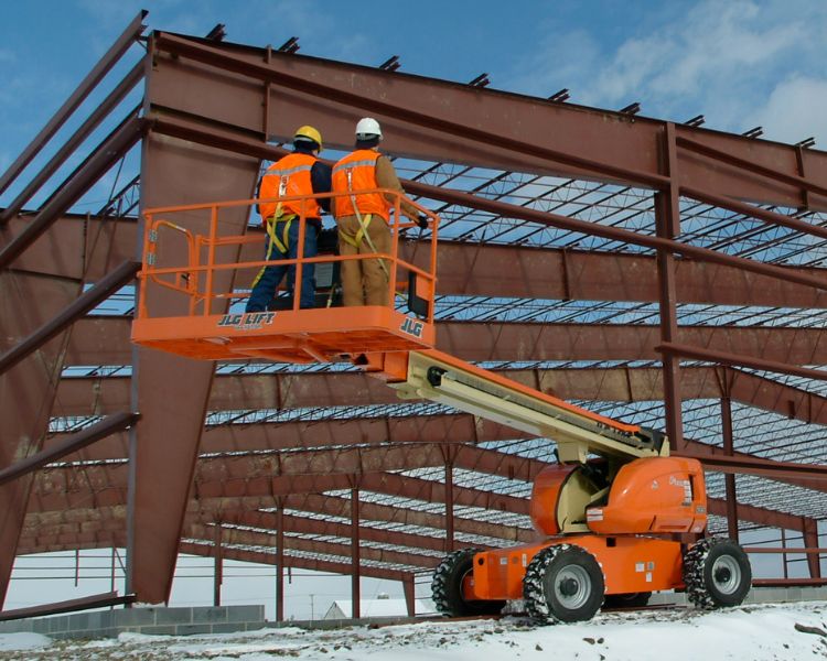 A JLG boom lift outdoors with two operators on the platform and a mast that is not extended.