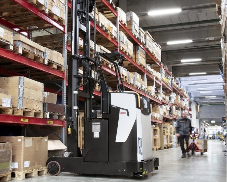 An automated forklift picking pallets from warehouse pallet racking.