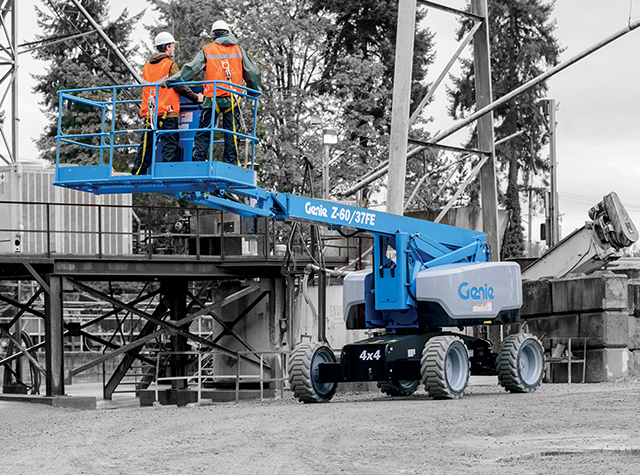 A Genie boom lift outside with the mast lowered and two operators on the platform.