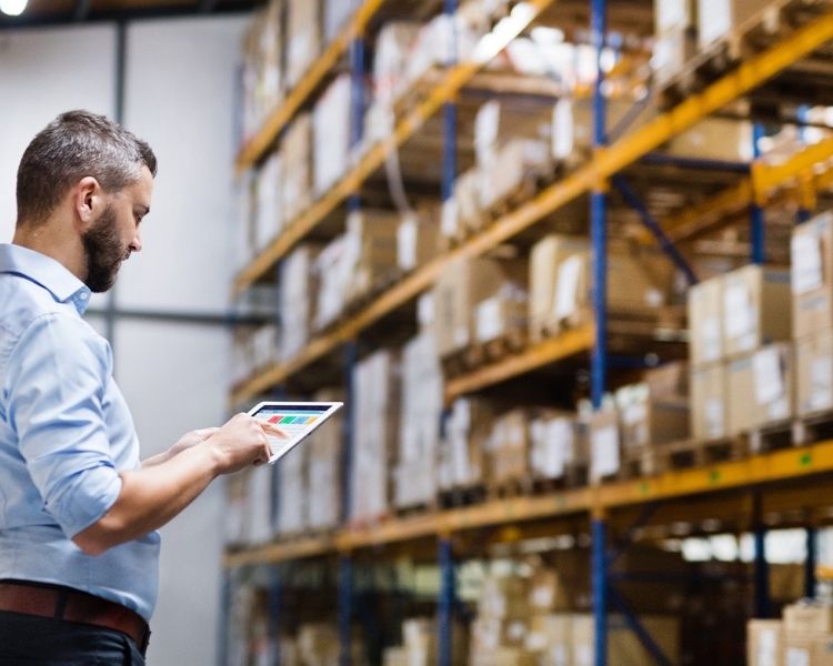 A man reviewing a warehouse racking layout drawing next to existing pallet racks in a warehouse.